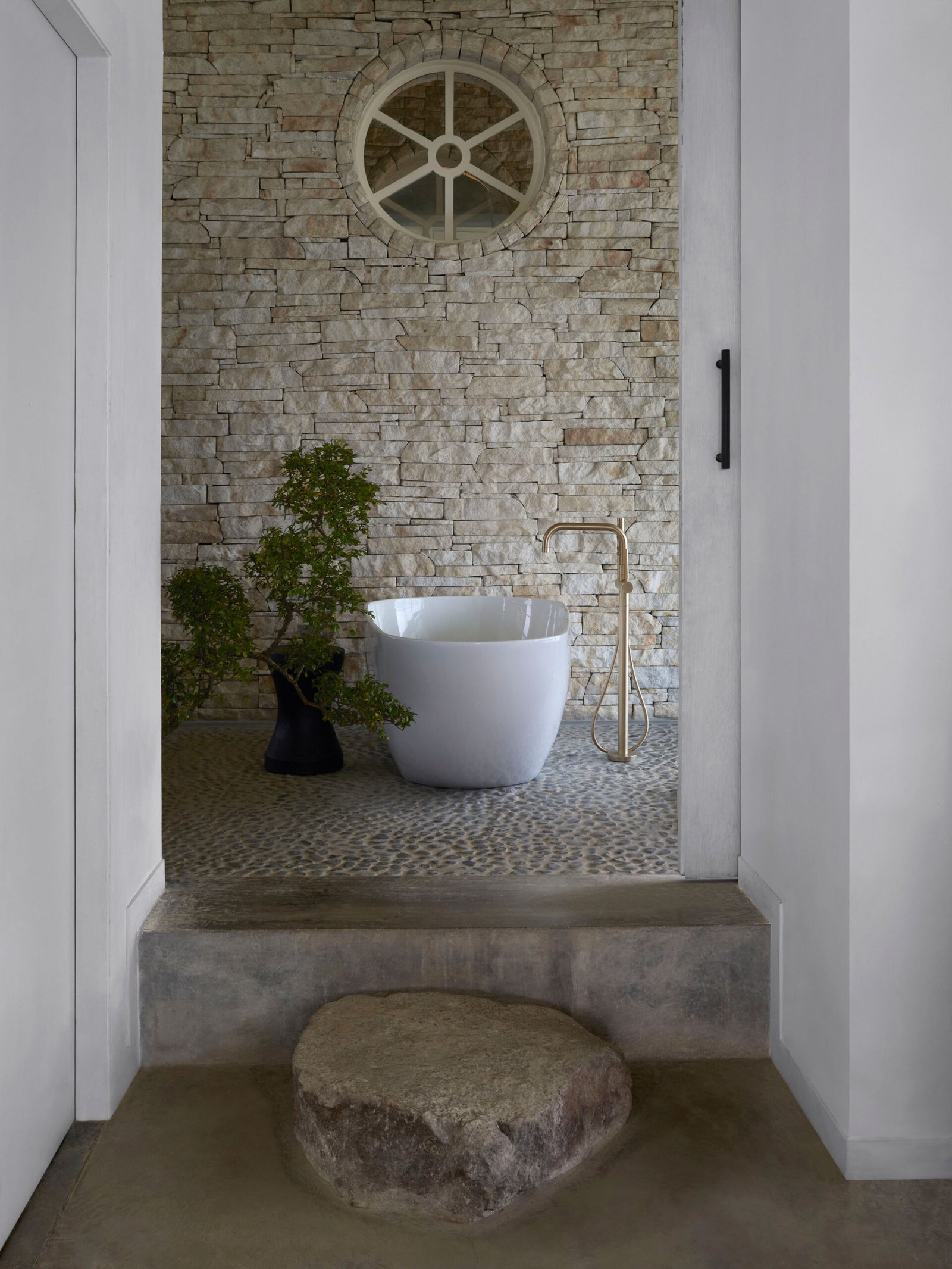 master bathroom with freestanding bath tub and pebble floor